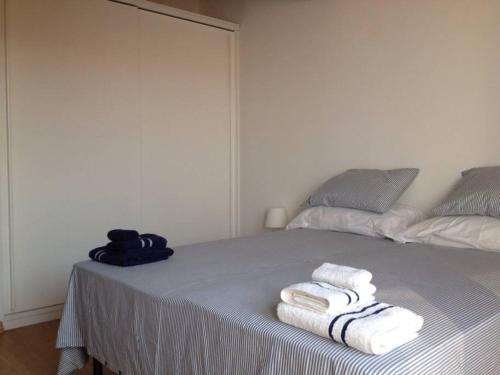 1 dormitorio con 1 cama con toallas en La Casa Blanca y Azul, en SantʼAntìoco