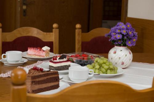 a table topped with cakes and fruit and a vase of flowers at Ferienwohnung Floriani in St. Wolfgang