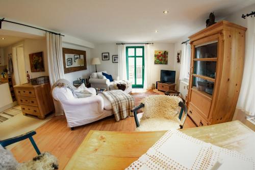 ein Wohnzimmer mit weißen Möbeln und einem Tisch in der Unterkunft Traumhaftes Elb-Chalet in Dresden