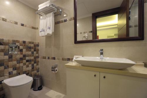 a bathroom with a sink and a toilet and a mirror at Ibiza Hotel in Jounieh