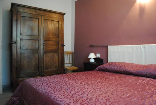 a bedroom with a red bed and a wooden cabinet at B&B GioAnn in Bernezzo