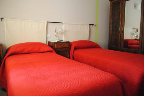 a bedroom with two beds with red sheets and a mirror at B&B GioAnn in Bernezzo