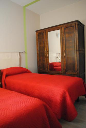 a bedroom with two beds and a cabinet with a red blanket at B&B GioAnn in Bernezzo