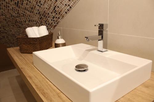 een witte wastafel in een badkamer met een mand met handdoeken bij Rooms H Ercolani in Bologna