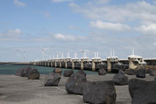 a pier with rocks in front of the water and windmills at Privé B&B Zeilboot Noorderlicht in Kamperland