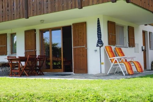a group of chairs and an umbrella in front of a house at Chalet Lucille in Leysin