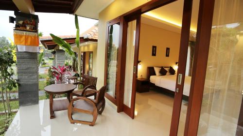 ein Schlafzimmer mit einem Bett und einem Tisch und Stühlen in der Unterkunft Darra Ria Villa Ubud in Ubud