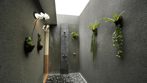ein Bad mit einer Dusche mit Pflanzen an der Wand in der Unterkunft Darra Ria Villa Ubud in Ubud