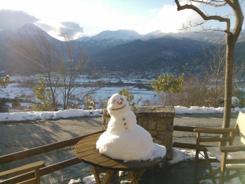um boneco de neve sentado numa mesa na neve em Olvios Hotel em Gkoura