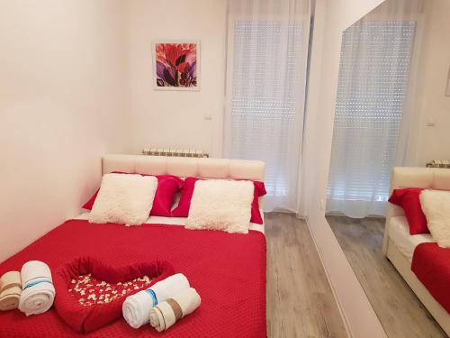a bedroom with a bed with a red blanket and pillows at Apartment GEA 1 in Novi Sad