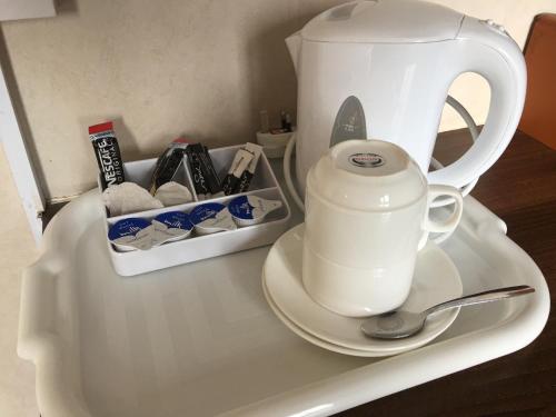 a white tea kettle on a white tray with a spoon at South Fork Guest House in Leicester