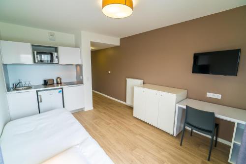 a room with a bed and a desk and a tv at All Suites Appart Hôtel - Choisy-le-Roi in Choisy-le-Roi