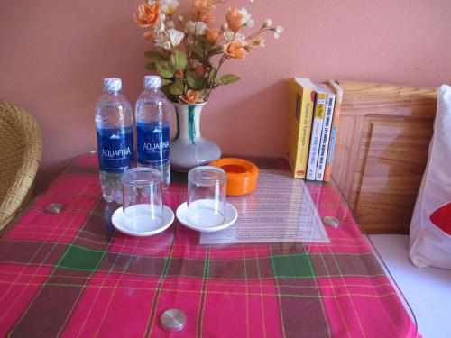 a table with two bottles and glasses and a vase with flowers at Sapa Backpacker Hostel in Sa Pa