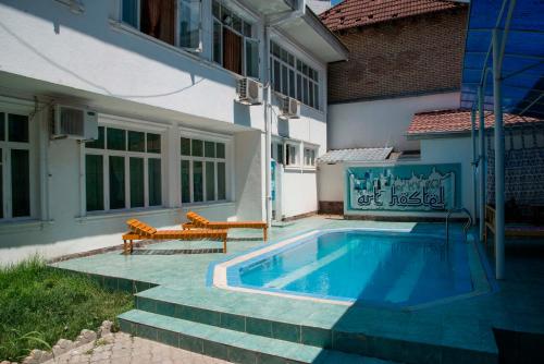 una piscina con 2 bancos junto a un edificio en Art Hostel, en Tashkent