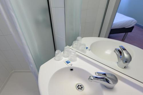 La salle de bains est pourvue d'un lavabo et d'un miroir. dans l'établissement Ibis Budget Bollene, à Bollène