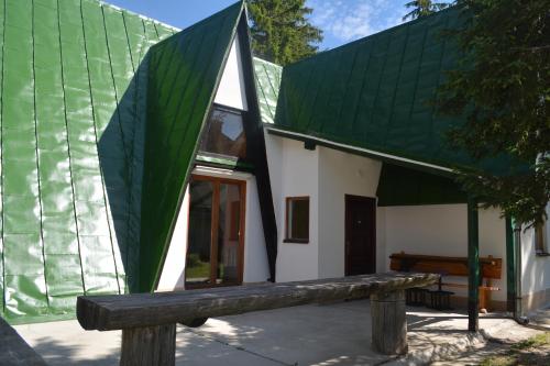 a building with a green roof and a wooden bench at Chalet Tupara in Vlasic