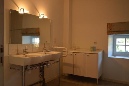 ein Bad mit einem Waschbecken und einem Spiegel in der Unterkunft Belle Dépendance du Château le Parc avec sa piscine in Ardentes