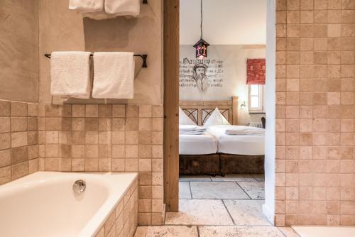 a bathroom with a bath tub and a bedroom at Hotel Arthus in Aulendorf