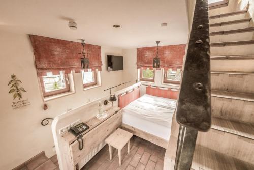 a room with a bed and a staircase and windows at Hotel Arthus in Aulendorf