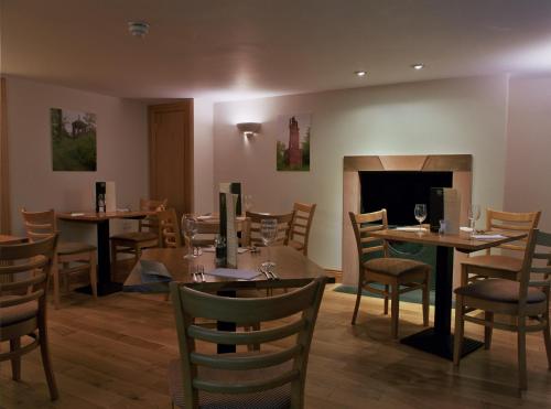 ein Esszimmer mit Tischen und Stühlen und einem Kamin in der Unterkunft The Spread Eagle Hotel in Jedburgh