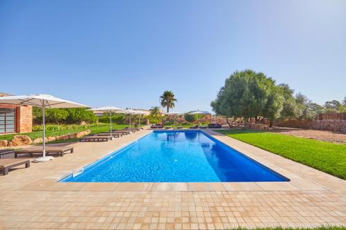 a swimming pool with benches and umbrellas in a park at Bennoc Petit Hotel - Only Adults in Llucmajor