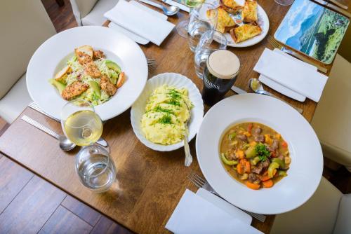 a wooden table with plates of food and glasses of wine at Lios Na Manach ECO B&B in Killarney