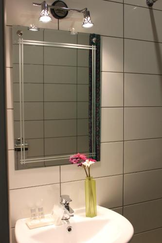 a bathroom sink with a vase with flowers in it at Atlas Hotel in Tomsk