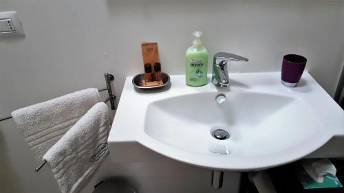 a white bathroom sink with a bottle of soap and a detergent at Orchidea Rooms & Suites in Civitanova Marche