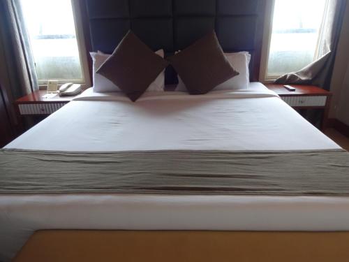 a bedroom with a large bed with white sheets and pillows at Paramount Tower in Kozhikode