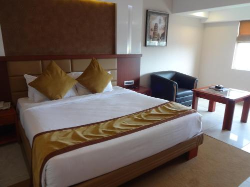 a hotel room with a large bed and a chair at Paramount Tower in Kozhikode