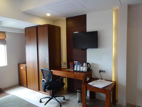 a room with a desk with a chair and a tv at Paramount Tower in Kozhikode