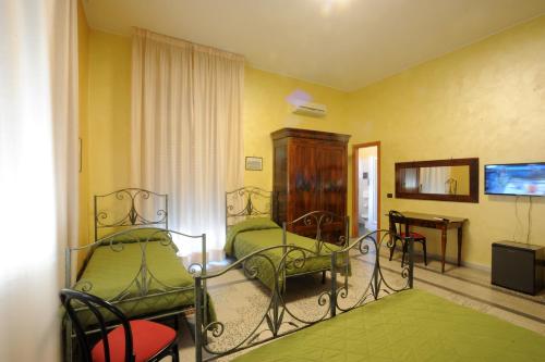 a room with two beds and a table and a television at Albergo Bellavista in Latina