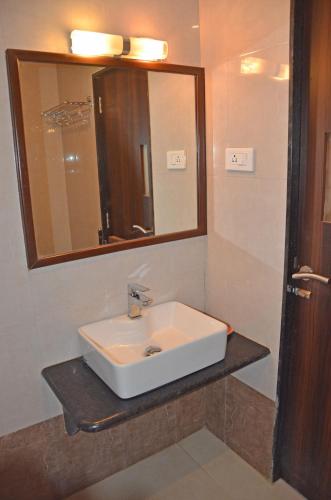 a bathroom with a white sink and a mirror at Hotel GreenLand-Elegant in Kolhapur