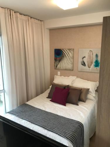1 dormitorio con 1 cama blanca grande con almohadas en Estúdio charmoso no coração do Brooklyn., en São Paulo