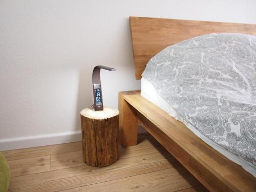 a bed with a remote control next to a wooden table at Apartment Harzgrün in Sankt Andreasberg