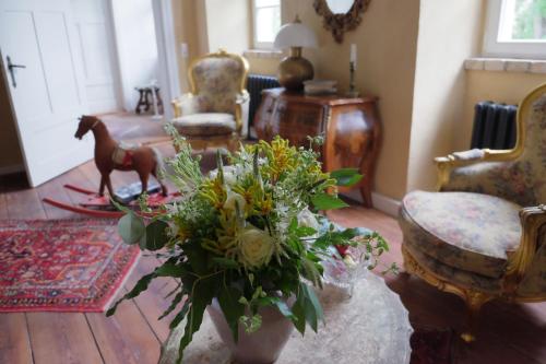 a living room with a table with a vase of flowers at Event- Kultur & B&B Kunst Schloss Neuenhagen Übernachten im Denkmal in Bad Freienwalde