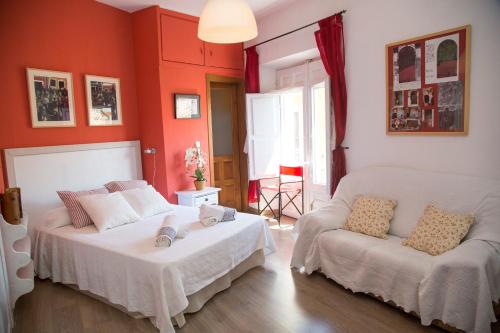 Un dormitorio con paredes rojas y una cama y un sofá. en Casa Garrote, en Cuenca