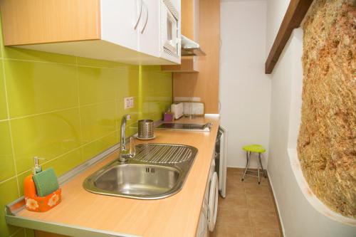 una pequeña cocina con fregadero y paredes verdes en Casa Garrote, en Cuenca