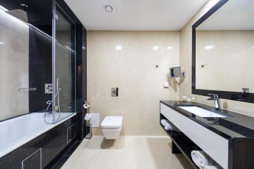 a bathroom with a sink and a toilet and a mirror at Ambasador Premium in Łódź