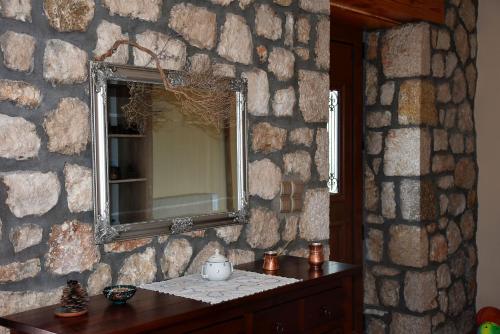 a stone wall with a mirror and a wooden table at Komilio 1 in Komílion
