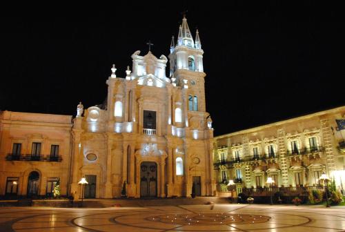 a large building with a clock tower at night at Jonio B&B in Acireale
