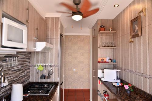 a kitchen with a stove and a ceiling fan at Apartamento Romantico in Caniço