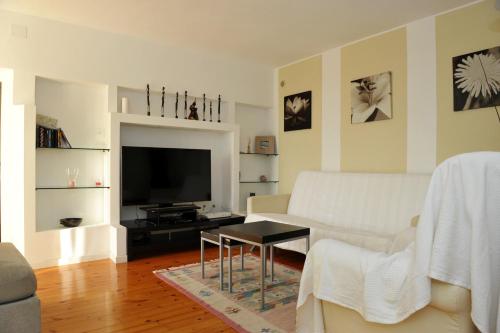un soggiorno con divano bianco e TV di Appartamento del Sole a Maccagno Superiore
