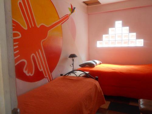 a bedroom with two beds and a painting of a peacock at Hostal La Casa del Sol in Copacabana