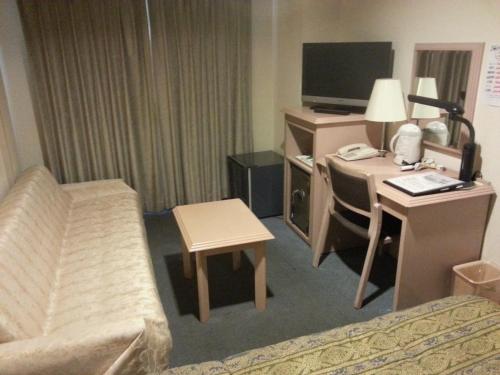 a hotel room with a bed and a desk with a computer at Hotel Hashimoto in Sapporo