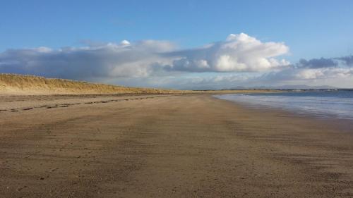 a sandy beach with water and clouds in the sky at Craig Eithin B & B in Holyhead