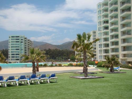 a group of chairs sitting on the grass near a building at Papudo Laguna Acceso Playa in Papudo