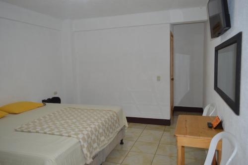 a bedroom with a bed and a table and a television at Hotel Xetawaa´l in San Pedro La Laguna