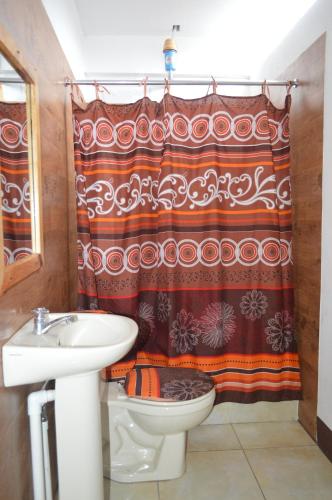a bathroom with a toilet and a shower curtain at Hotel Xetawaa´l in San Pedro La Laguna