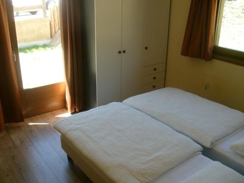 1 dormitorio con cama, ventana y puerta en Baita Fetaplana, en Livigno